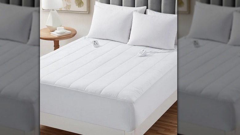White heated mattress pad with two controls on bed