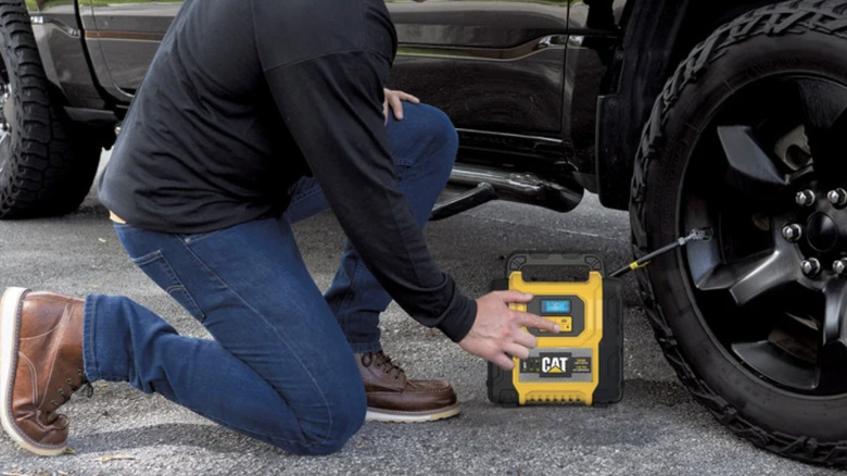 Man inflating tire with CAT 2500 Amp Lithium Jump Starter and Air Compressor