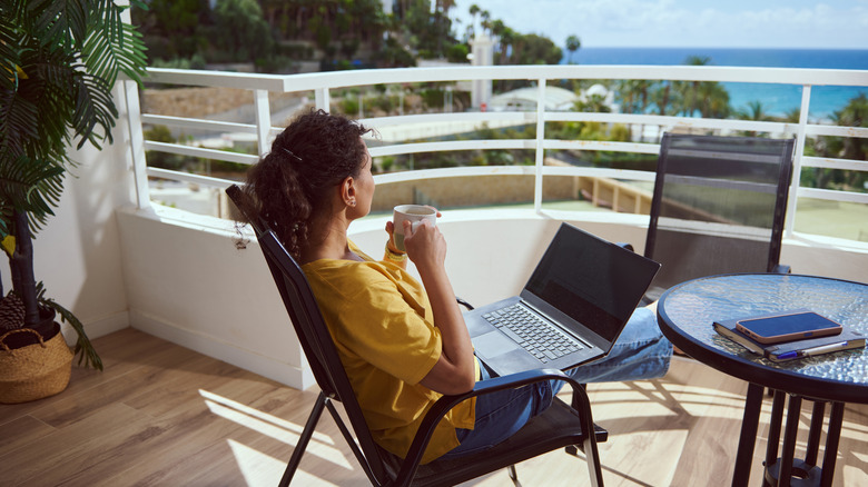 Woman working remotely from sunny balcony