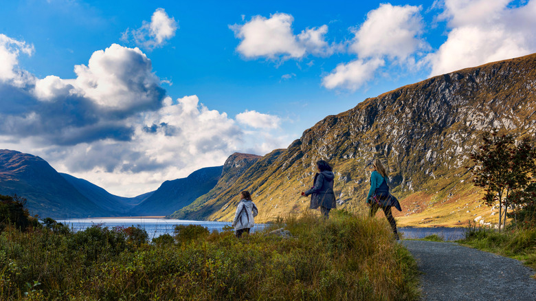 Three Tourists walk along a walkway at the lake in Glenveagh National Park, County Donegal, Ireland