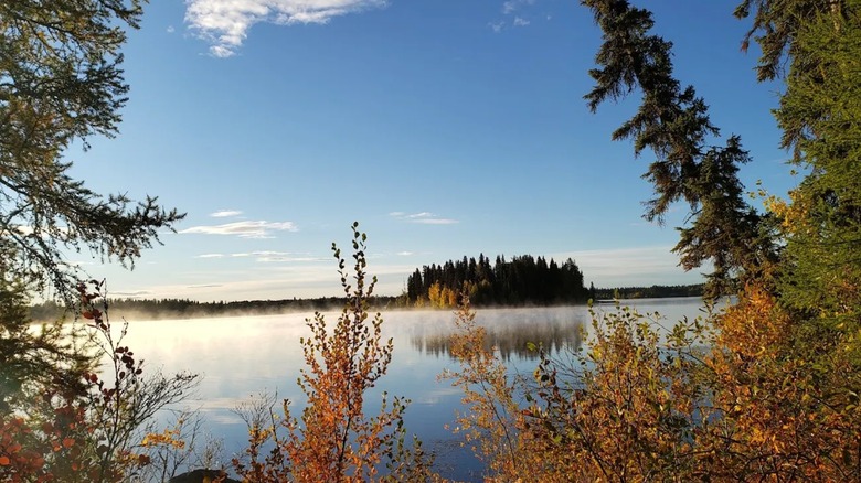 Mist coming off the surface of a lake in Crimson Lake Provincial Park, surrounded by fall foliage