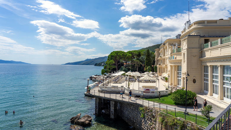 Elegant hotel facade and people swimming in Adriatic sea, Opatija, Croatia