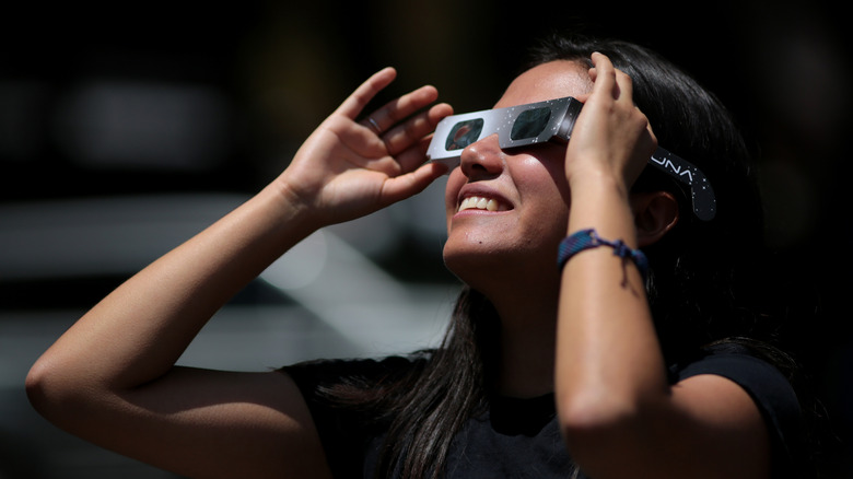 Girl watching the solar eclipse with eclipse glasses