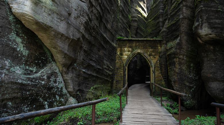 Stone gate and wooden walkway leading into cavernous rock formation