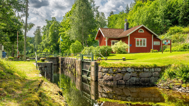 Typical red house in the Swedish Dalsland region countryside overlooking verdant canal docks.