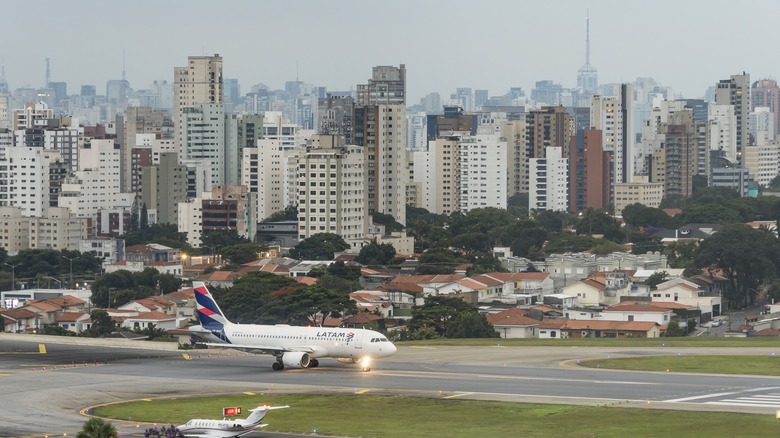 Plane on the runway at Congonhas Airport with city buildings in the back
