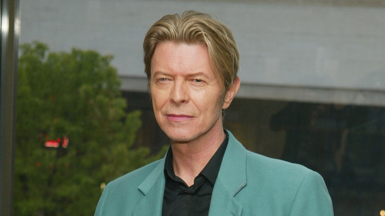 David Bowie with blonde hair and wearing a teal suit.