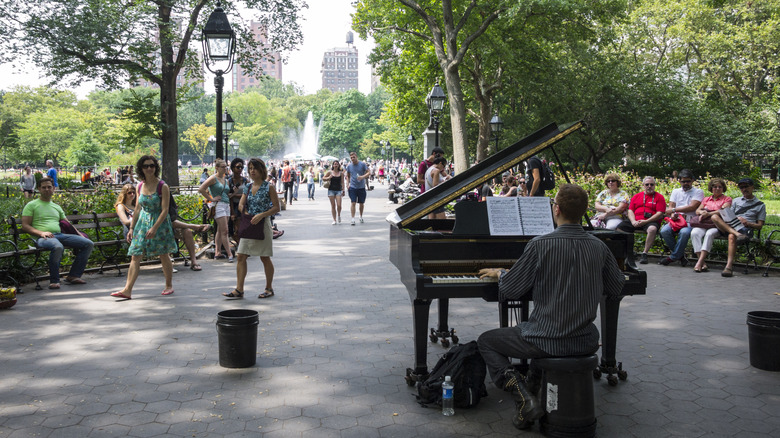 Man playing a piano in Washington Square Park, surrounded by onlookers