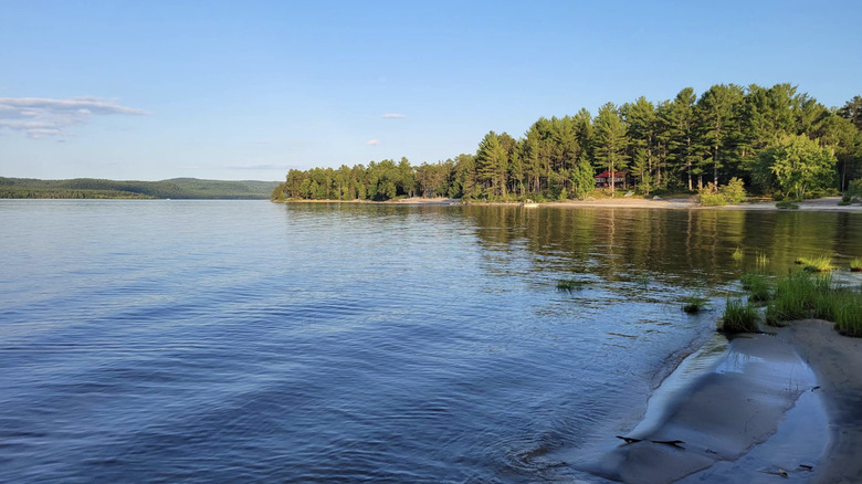 The calm water surrounded by sandy beach and forest on a bright day in Pine Point Beach in Deep River, Ontario