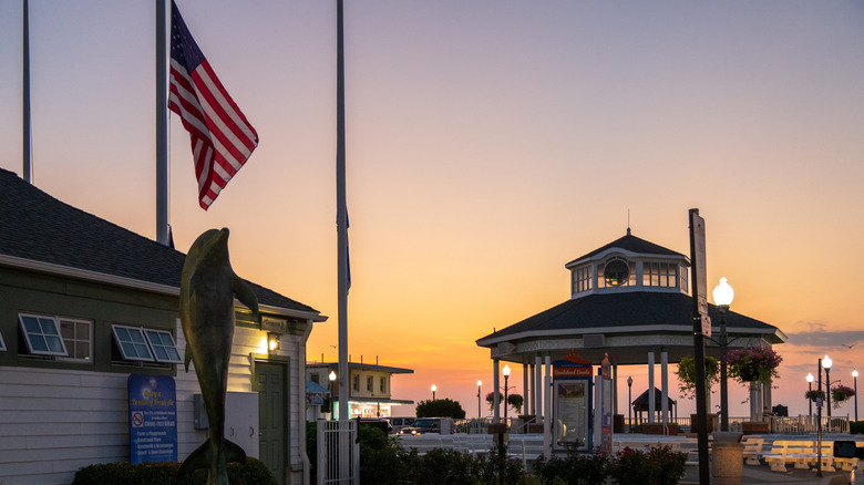 Rehoboth Beach bandstand at sunrise with a dolphin statue in the foreground.