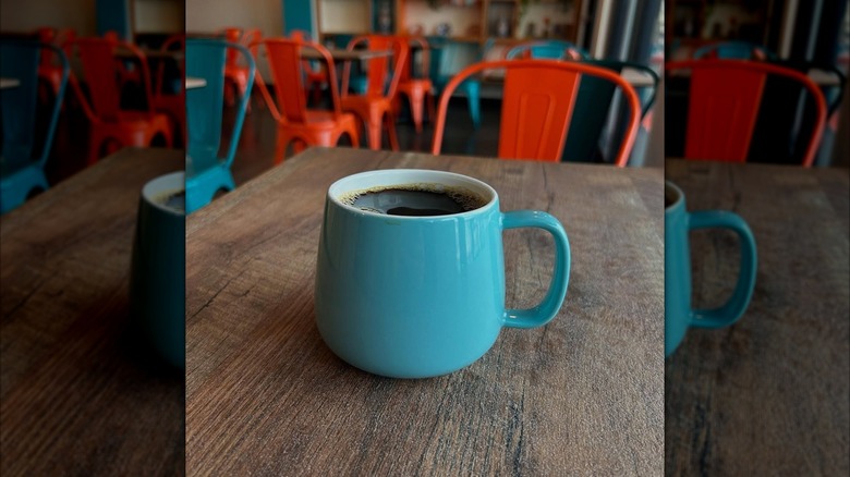 A blue mug of coffee on a wooden table