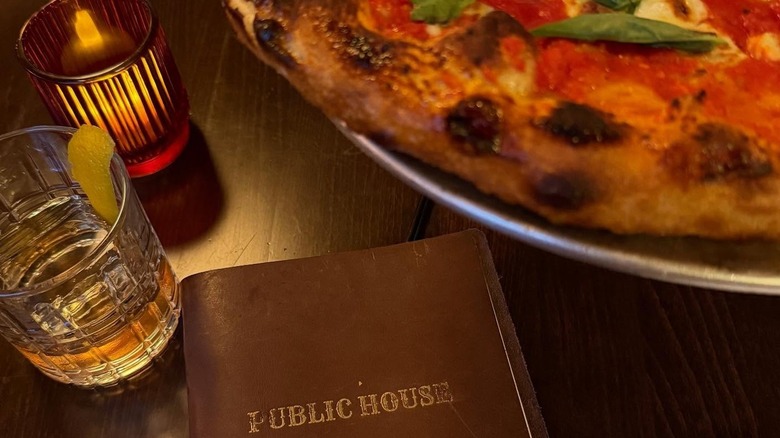 Pizza and a cocktail with the Public House menu on a table