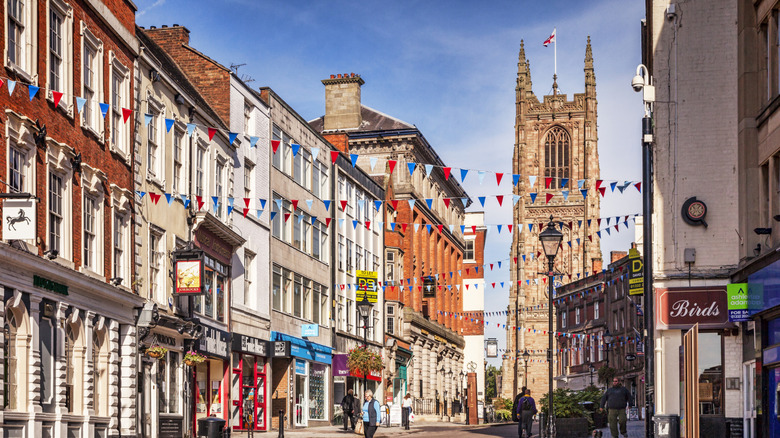 Red, white, and blue party flags strung between stores with a church in the background in Derby
