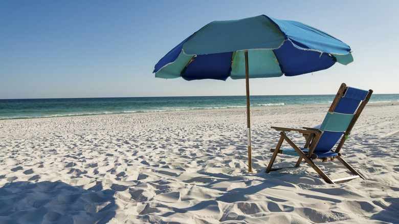A longe chair under an umbrella on the beach at Destin, Florida.