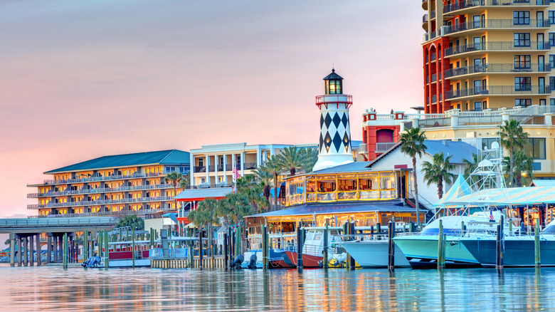 Destin, Florida harbor with boats in the marina with buildings and a fake lighthouse in the background.