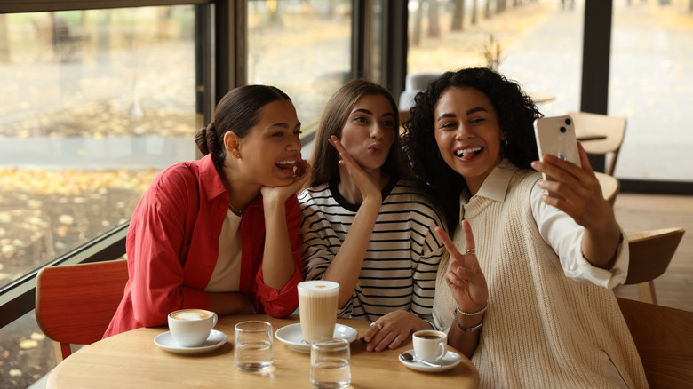 Three friends taking a self inside a cafe.