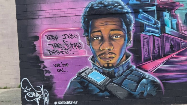 A boy painted in a futuristic style with the words "Step into the future Detroit ... We live on ..." next to him