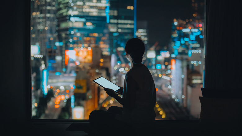 Silhouette of a woman with work tablet against a city skyline