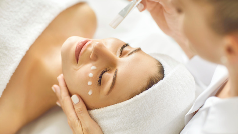 Someone receiving a facial treatment with a cream dotted under the eyes