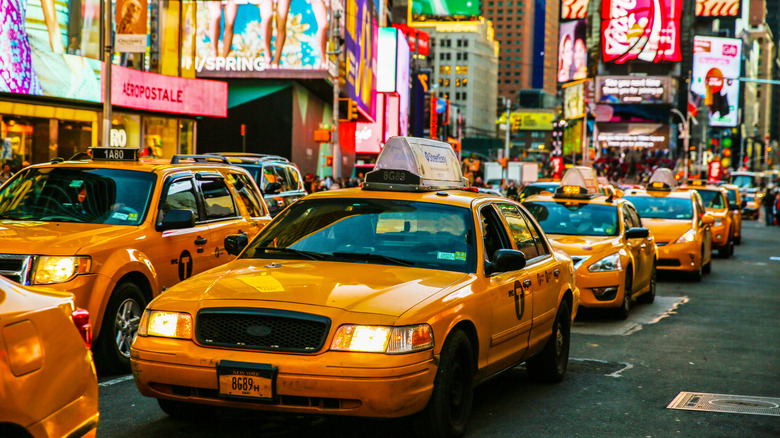 Line of yellow cabs in Times Square New York City bright billboards behind them