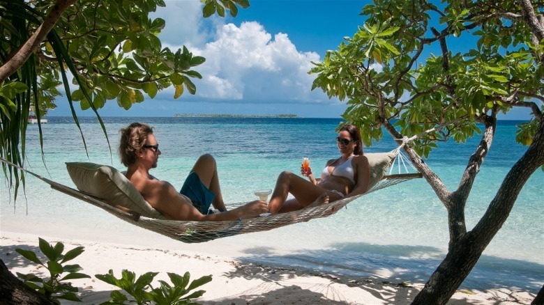 Guests relax in hammock in front of beach