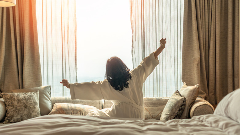 Someone stretching their arms, waking up refreshed in a hotel room