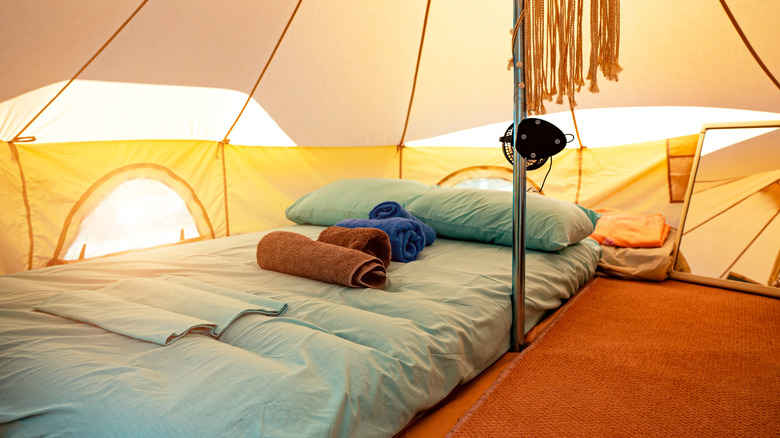 Inside of a camp tent with carpet, sleeping bag, and towels