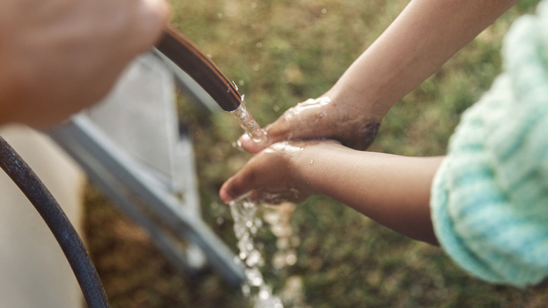 Washing dirty hands with a hose pipe