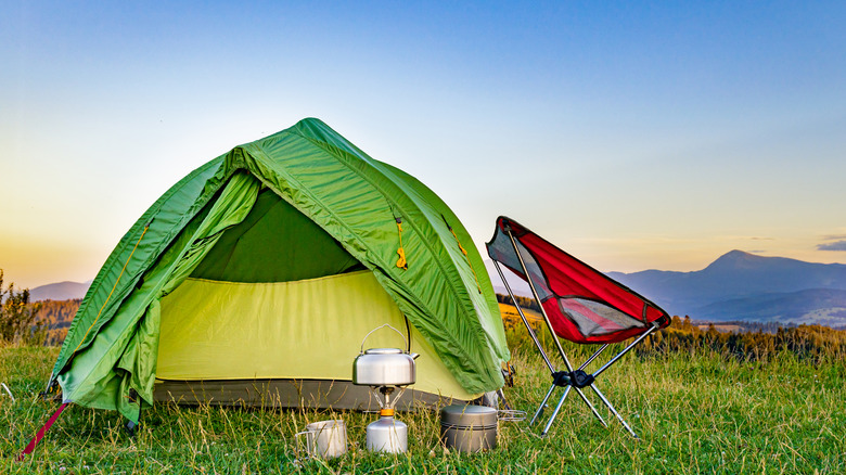 A green tent surrounded by hiking gear