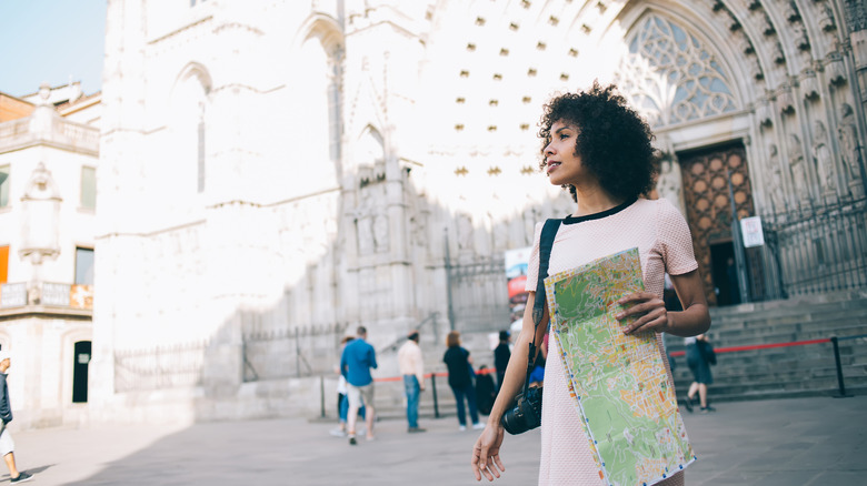 A woman holding a map outside a European church