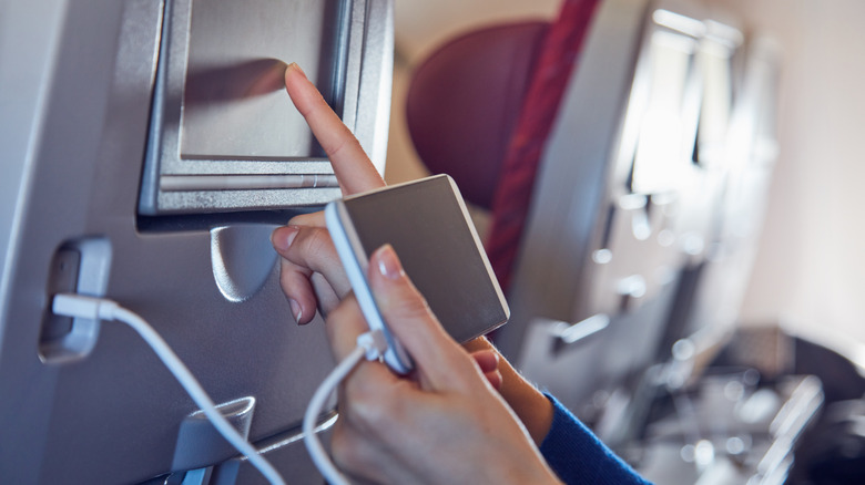 Person charging phone on airplane