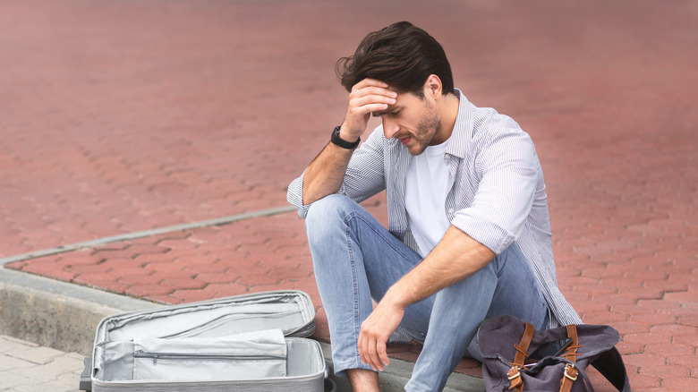 Dejected exasperated traveler searches luggage for lost item