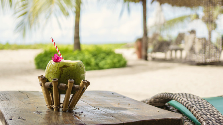 Coconut cocktails on a wooden table with tropical beach in background