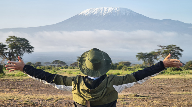 man in front of mount klimanjaro in tanzania