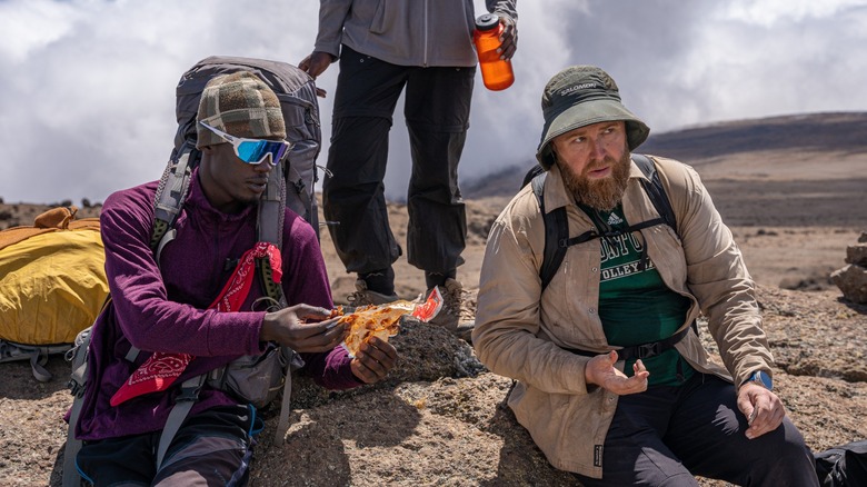 porter helping climber on kilimanjaro with dates