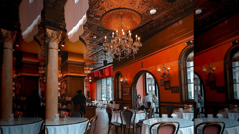 Interior of Cafe Intermezzo with chandeliers, wooden finishes, and people sitting at a table.
