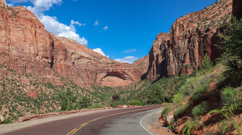 Red asphalt Zion-Mt. Carmel highway curving below the Grand Arch and blue sky