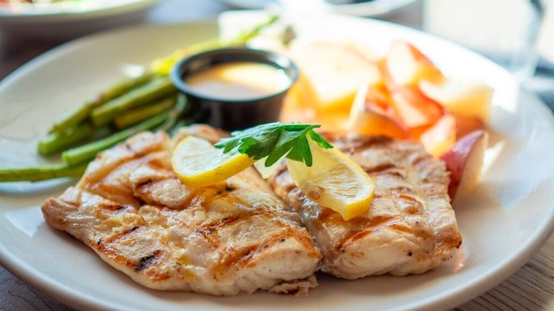 Close-up image of a plate of locally caught Florida red snapper garnished with a lemon slice, one of the seafood entrées served at Dry Dock Waterfront Grill