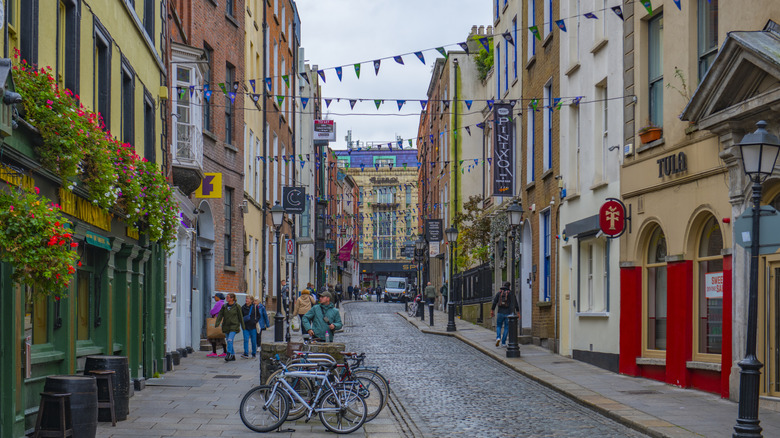 Historic commercial buildings with bikes and shoppers on a cloudy day on Essex Street E at Eustace Street in Temple Bar, Dublin, Ireland.