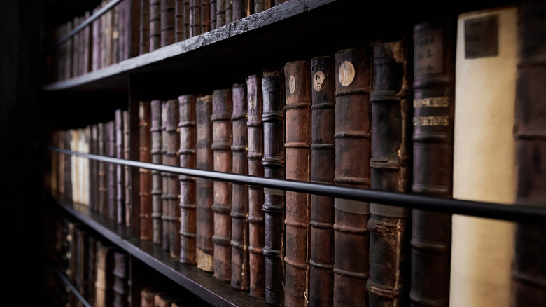 A close-up view of aged leather-bound books on 18th-century dark wooden shelves in Marsh's Library, Dublin