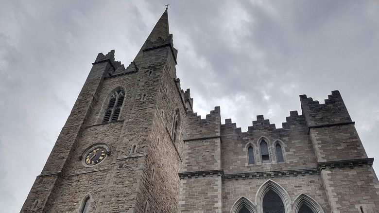 Upward exterior view of the imposing grey, stone St. Michan's Church in Dublin, Ireland on a cloudy day