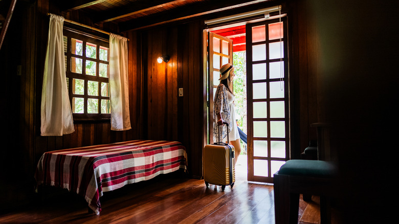 Female tourist with a suitcase in a wooden hotel room