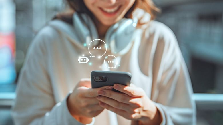 Woman in a white hoodie typing happily on her phone
