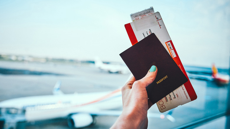 A traveler carries a passport and boarding pass at the airport