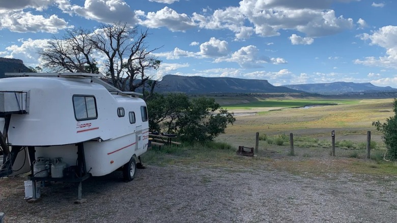 A camper on the campground at El Vado Lake State Park overlooking rocky mountains and fields on a sunny day