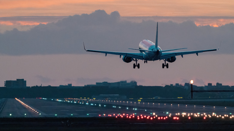 An airplane landing during sunrise