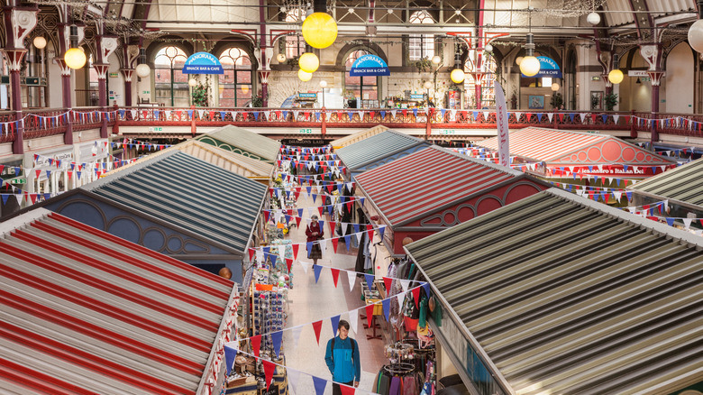 Red, white, and blue party flags, stripy vendor roofs, and a Victorian mezzanine inside Derby Market Hall