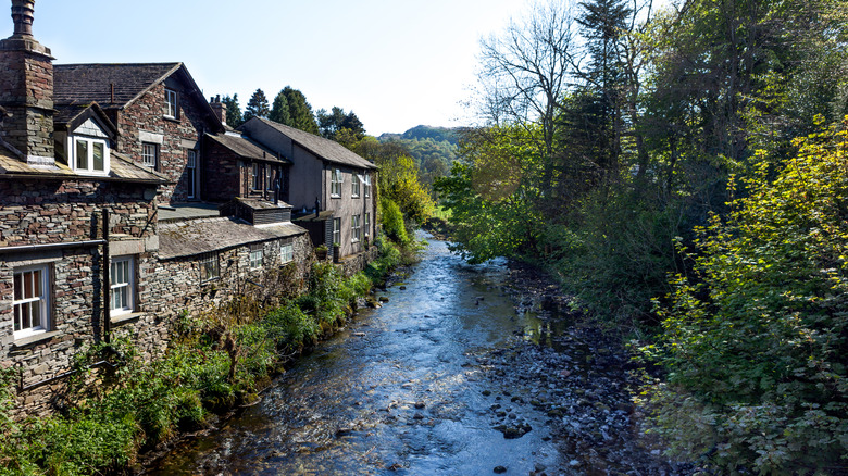 Stone cottages by a waterway and trees in Grasmere