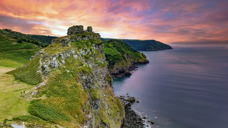 A craggy rock tops a hill beside the sea in the Exmoor National Park.