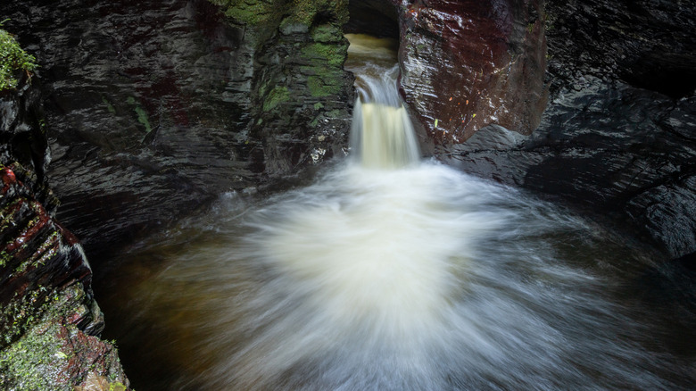 Small waterfall into rushing whirlpool in Lydford Gorge, Devon